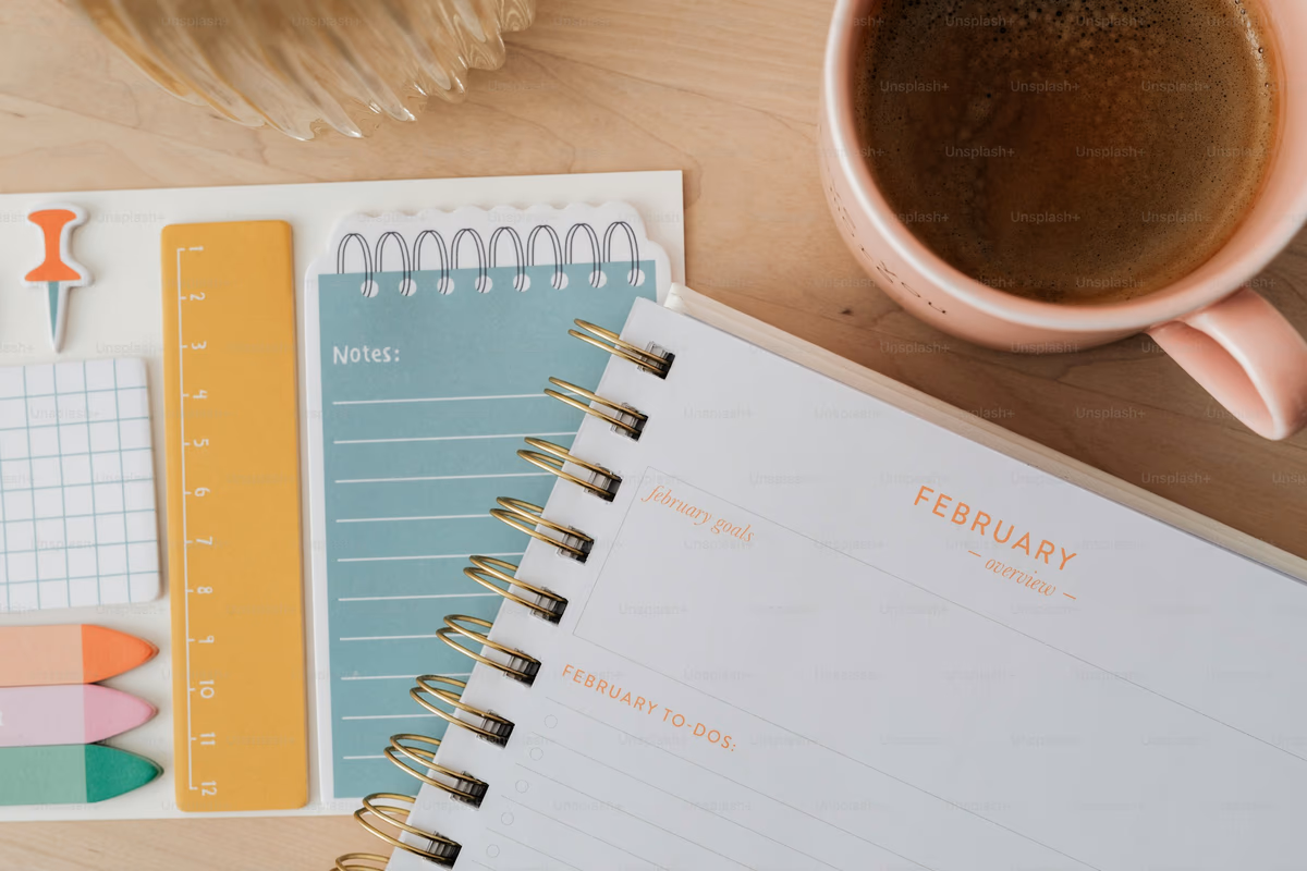 A desk planner with sticky notes and a coffee cup, marking an upcoming deadline