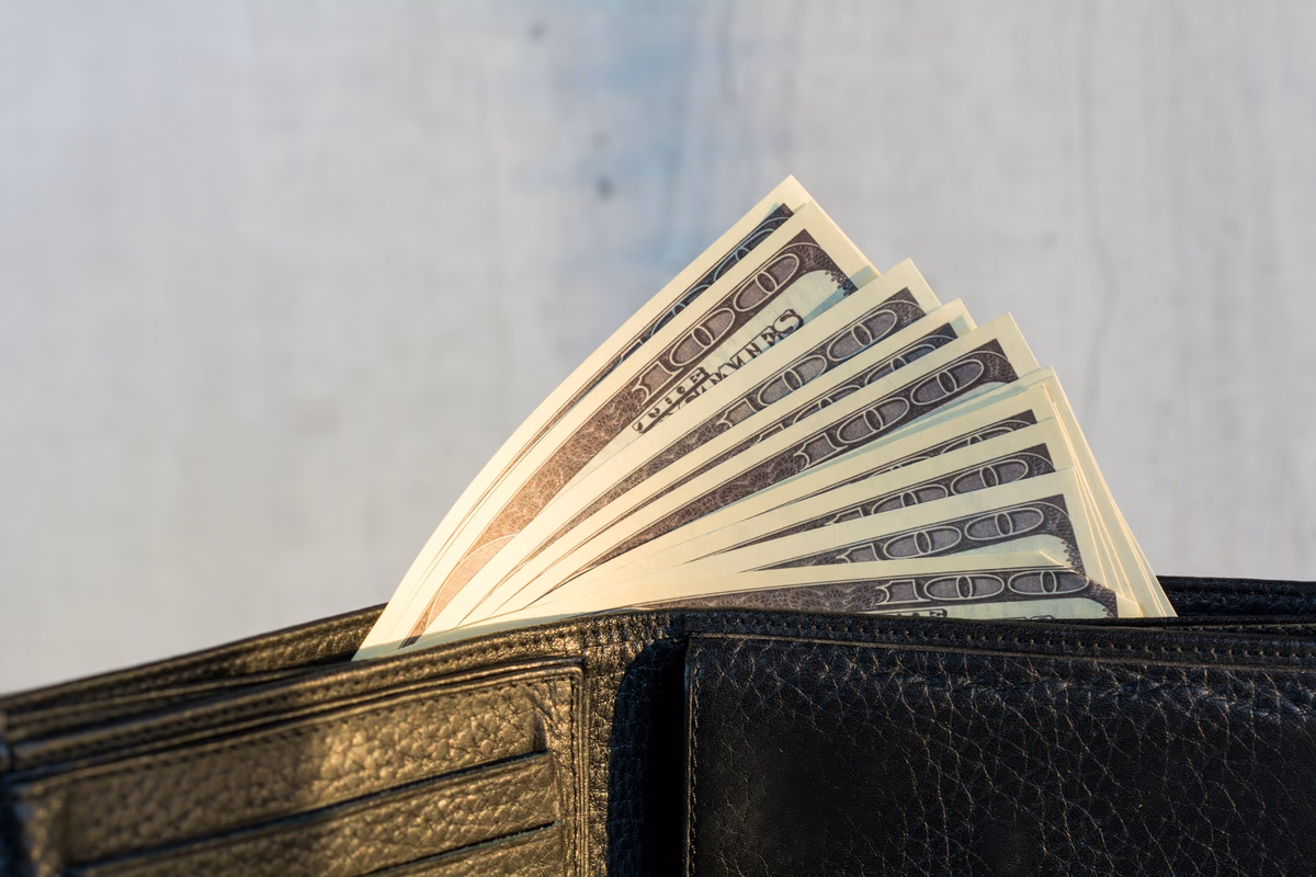 A wallet stuffed with twenty dollar bills sitting on a table